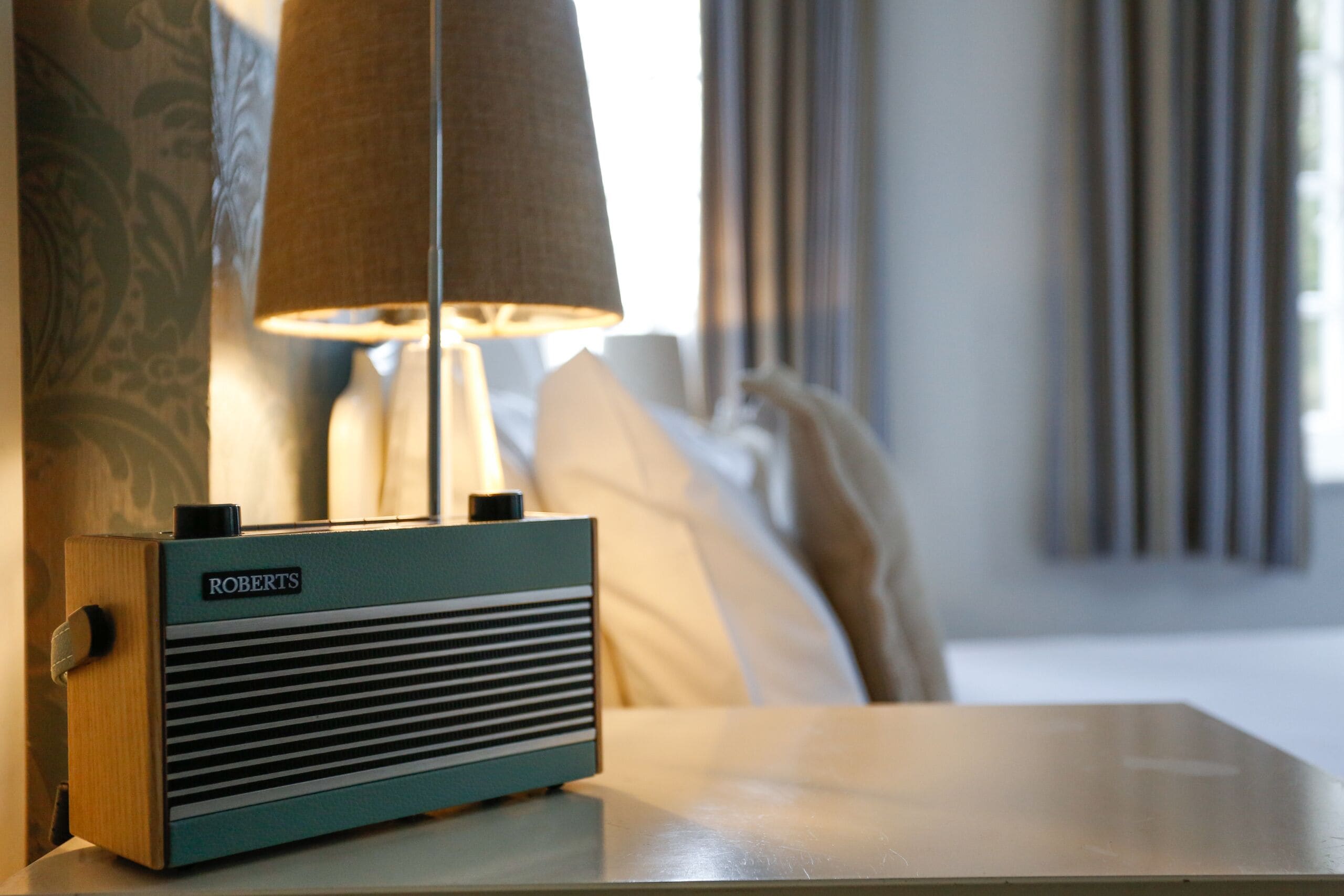 A radio on a table with a lamp in the background.