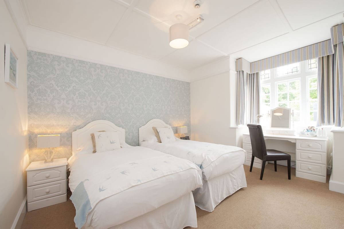A bedroom with two beds, a desk, and a chair.