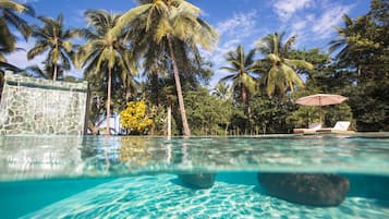Una piscina al aire libre, sombrillas, tumbonas