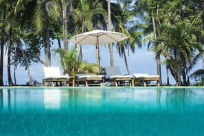 A poolside area with lounge chairs and a canopy, surrounded by palm trees. - Clandestino Beach  (Parrita)
