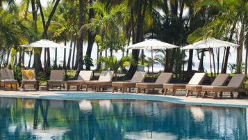 Una piscina al aire libre, sombrillas, sillones reclinables de piscina