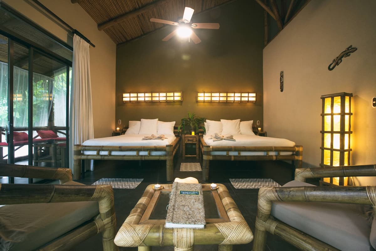 A room with two beds, a ceiling fan, and a table with a placemat.