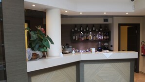 A reception area with a counter, potted plants, and a wall of liquor bottles. - Raya Hotel Motel (Mediglia)