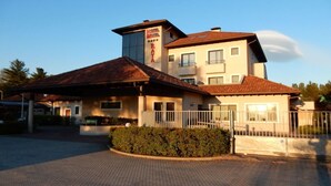 A hotel with a two-story building, a covered parking area, and a well-maintained garden. - Raya Hotel Motel (Mediglia)