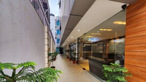A hotel corridor with potted plants, a seating area, and a modern interior design. - Hotel Lee International (Kolkata)