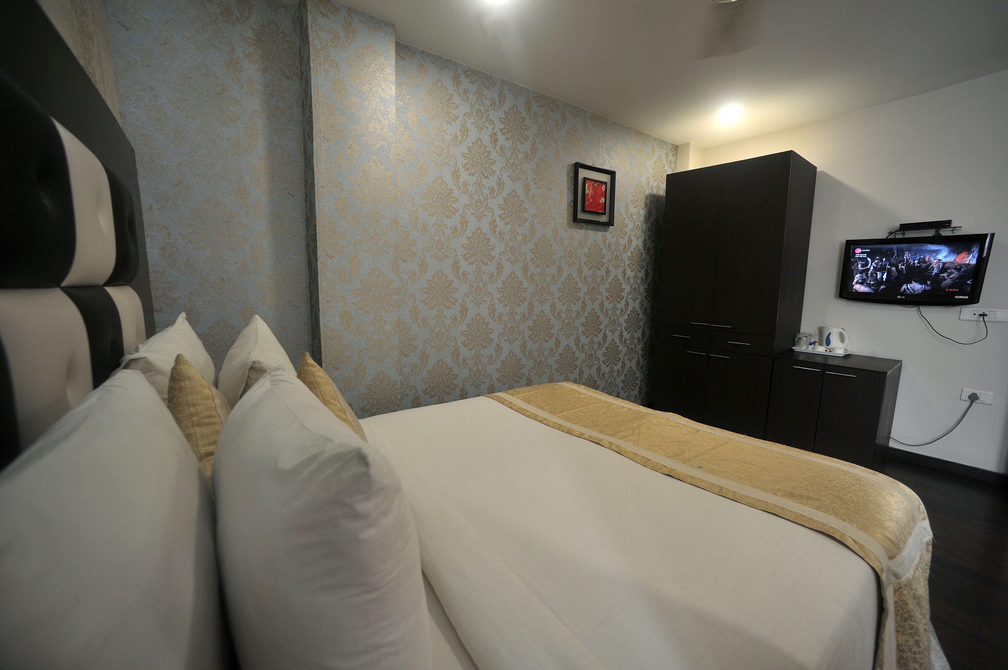 Une chambre d’hôtel équipée d’un lit, d’oreillers, d’une télévision et d’une armoire.