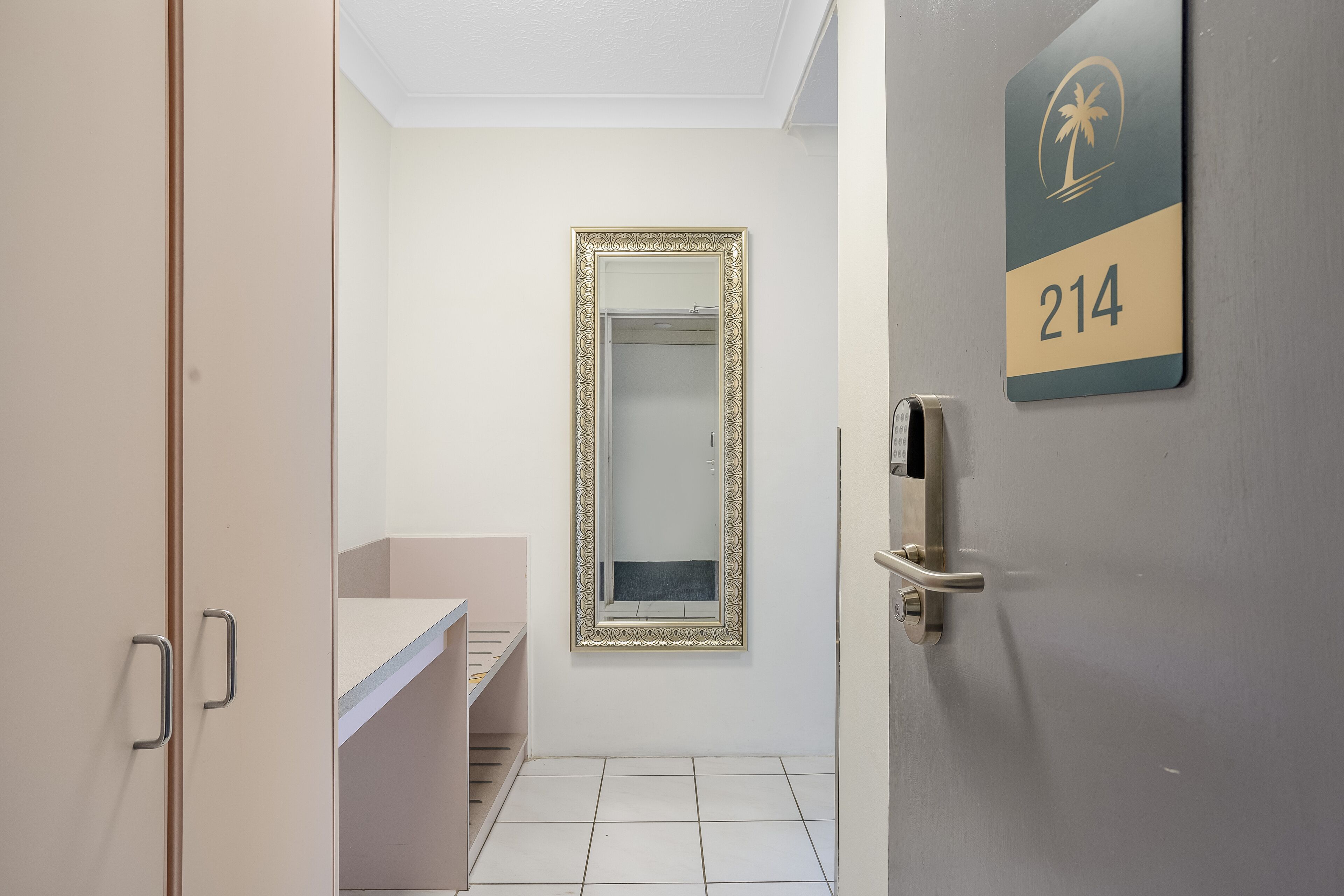 A hotel room with a bathroom, a door with a number sign, and a mirror.
