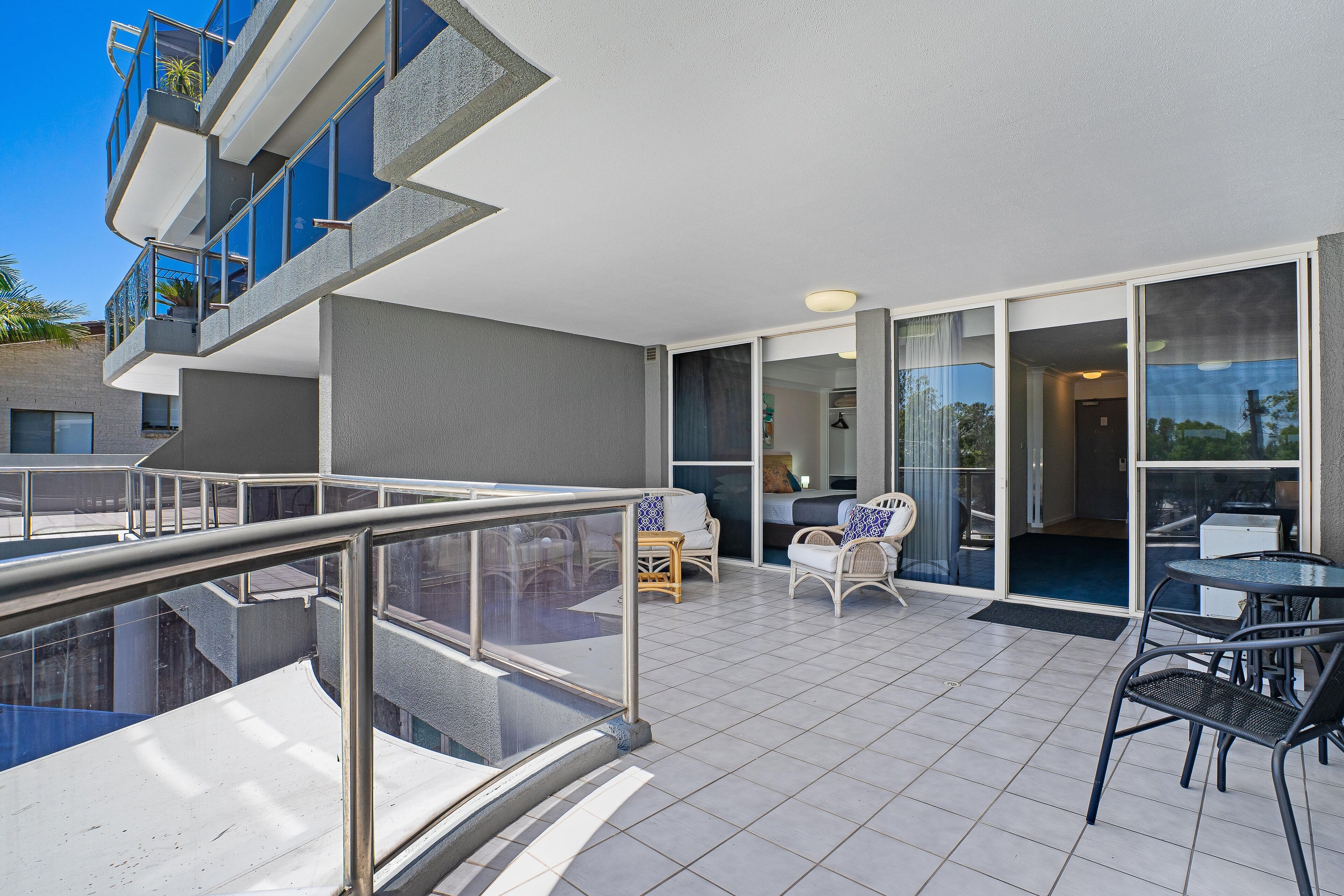 A modern apartment with a balcony, a pool, and a dining area with outdoor furniture.