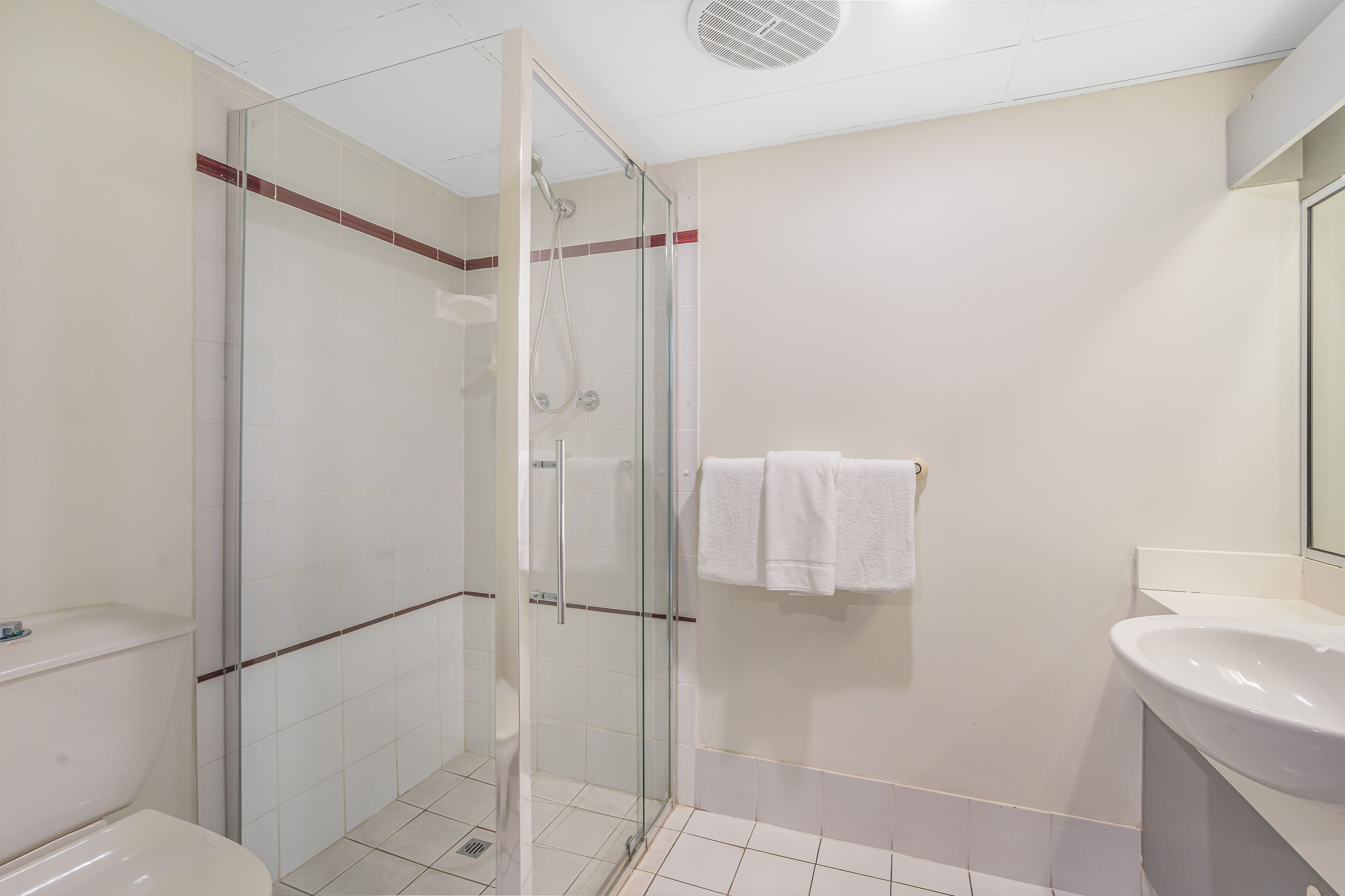 A modern bathroom with a glass-enclosed shower, a white sink, and a toilet.
