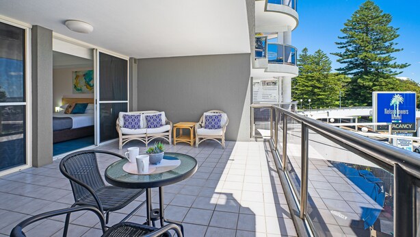 A balcony with a table, chairs, and a bed. - Nelson Towers Motel & Apartments (Nelson Bay)