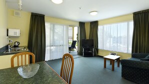 Een knus woongedeelte met een eettafel, een bank, een televisie en een kitchenette.