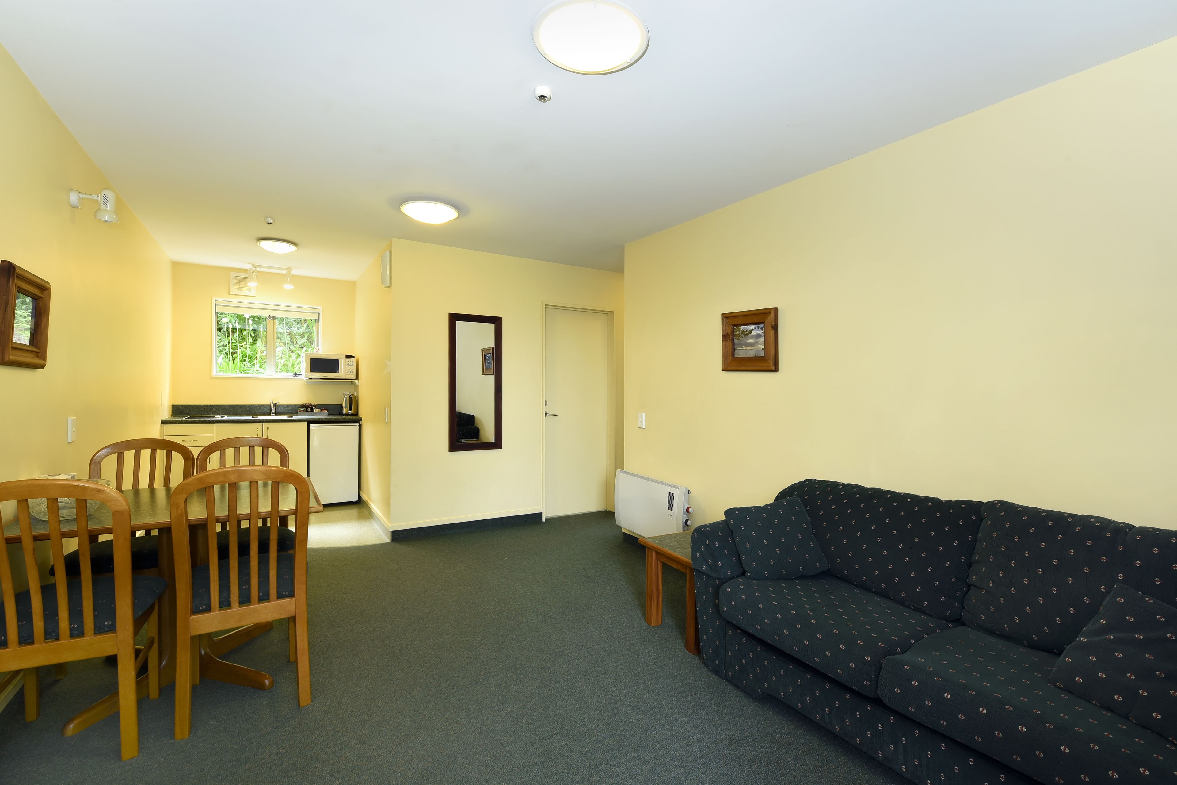 A compact living space with a dining area, kitchenette, and a sofa.