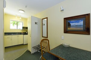 A compact kitchen with a dining area, a microwave, and a framed picture of a beach.