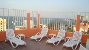 A balcony with white plastic chairs and a tiled floor, overlooking a body of water with boats and buildings. - Hotel Posada del Carmen (Veracruz)