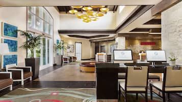 A hotel lobby with a reception desk, seating area, and large windows.