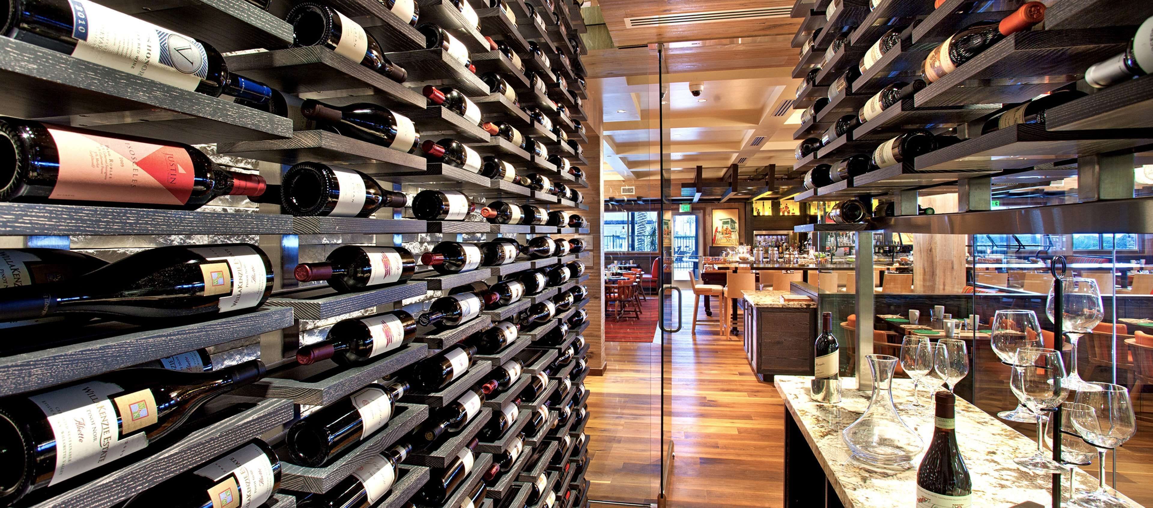 Une cave à vin avec des étagères remplies de bouteilles et un coin bar avec des verres et des bouteilles.