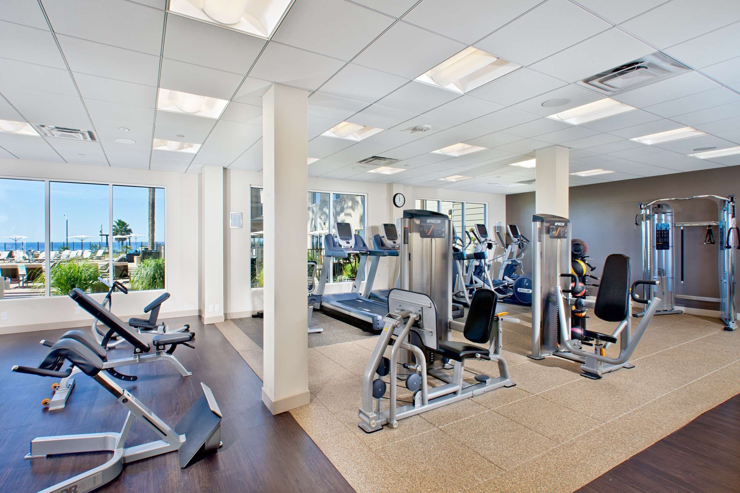 A gym with cardio machines, weight stations, and a treadmill.