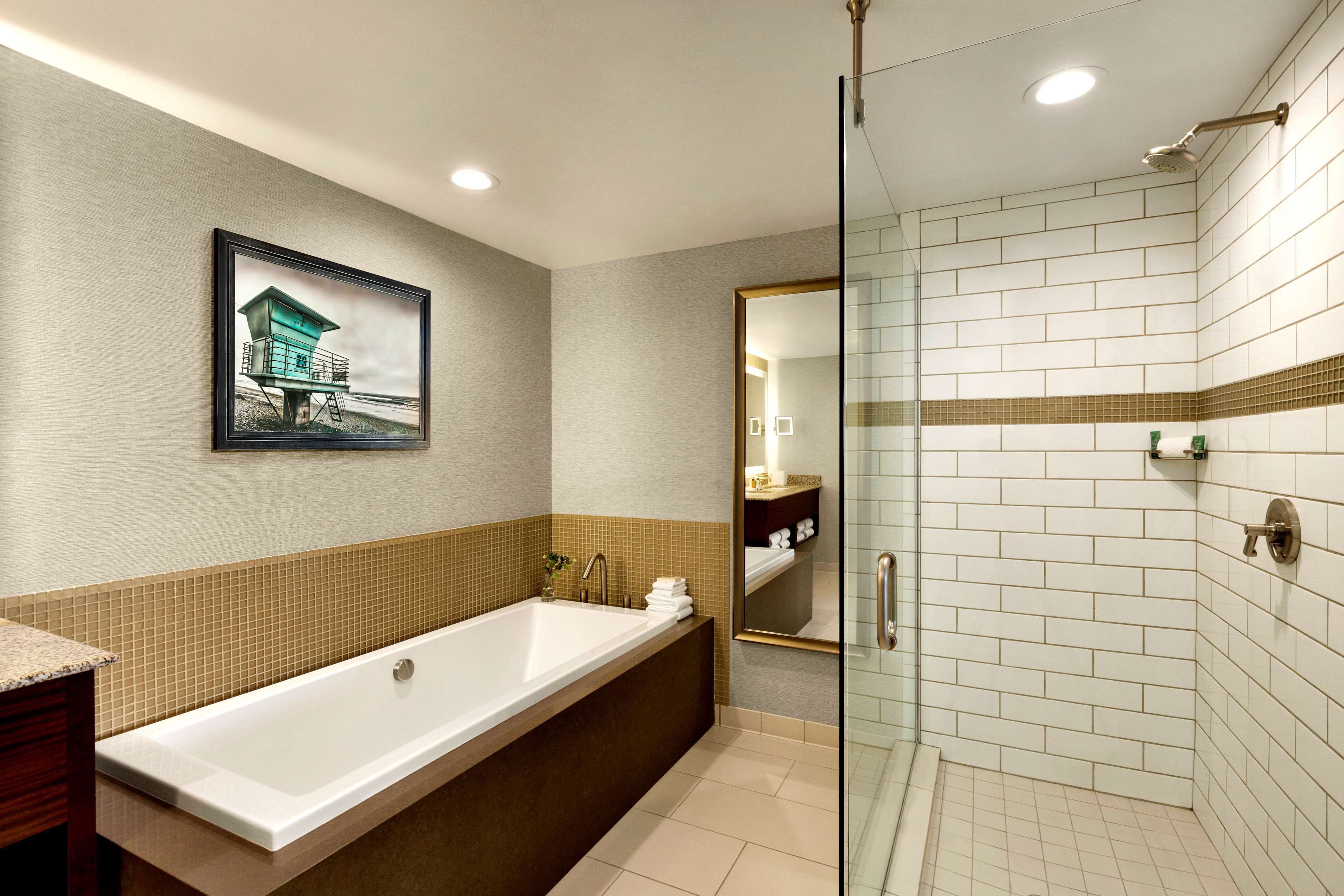 A modern bathroom with a large bathtub, a glass shower enclosure, and a framed picture on the wall.