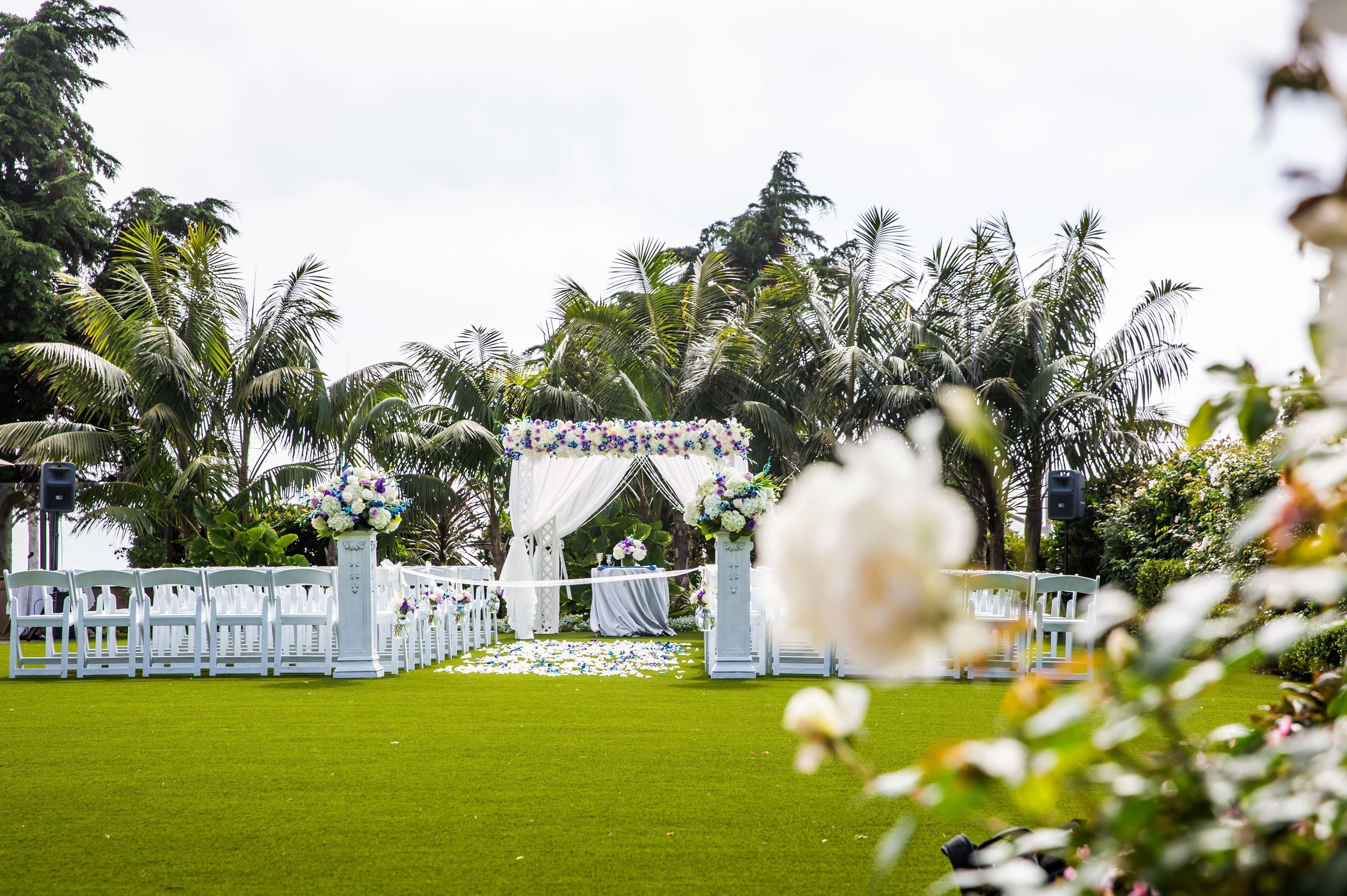 A wedding ceremony setup with white chairs and a floral arch.