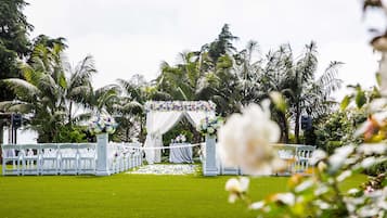 A wedding ceremony setup with white chairs and a floral arch.