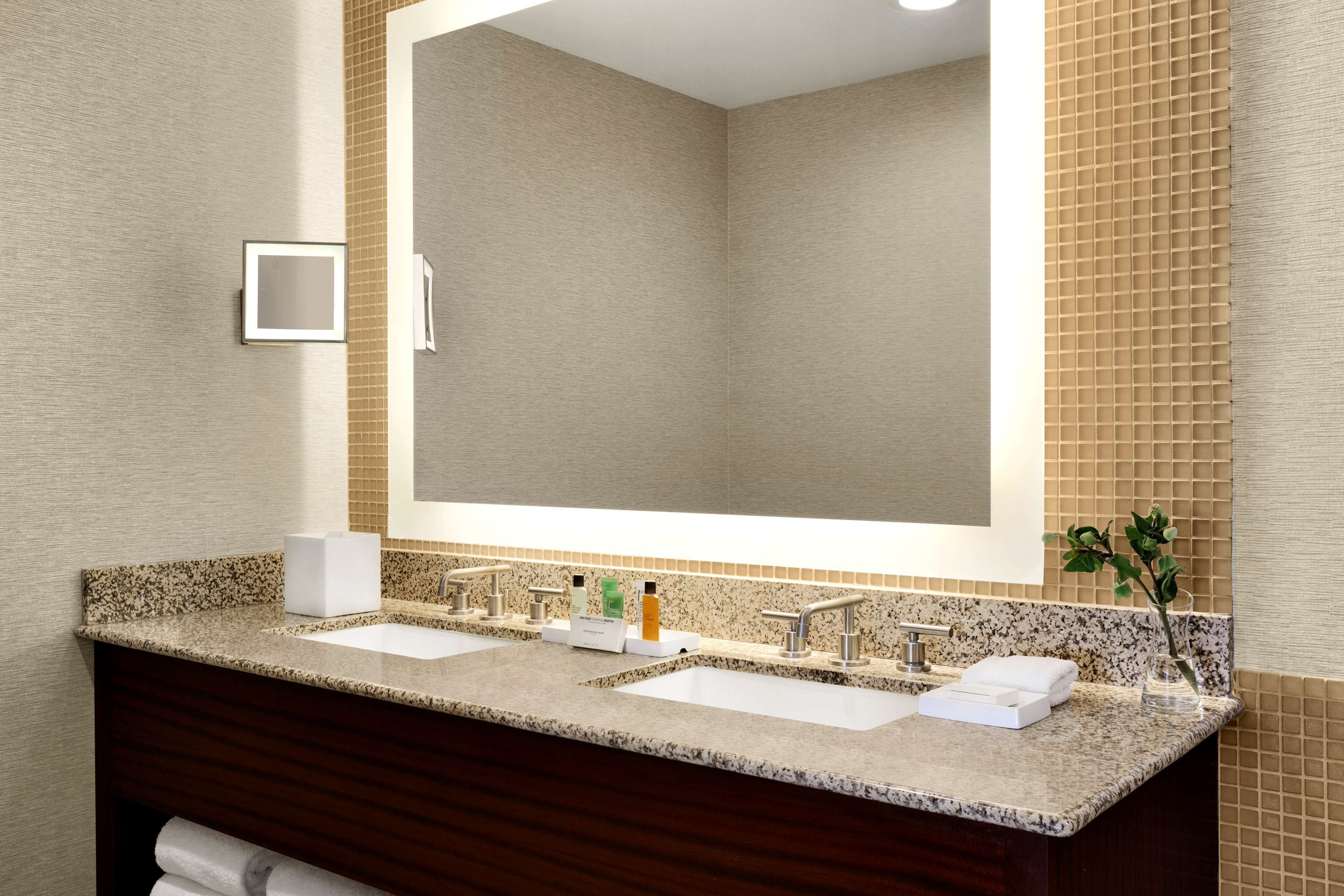 A modern bathroom with two sinks, a large mirror, and a towel rack.