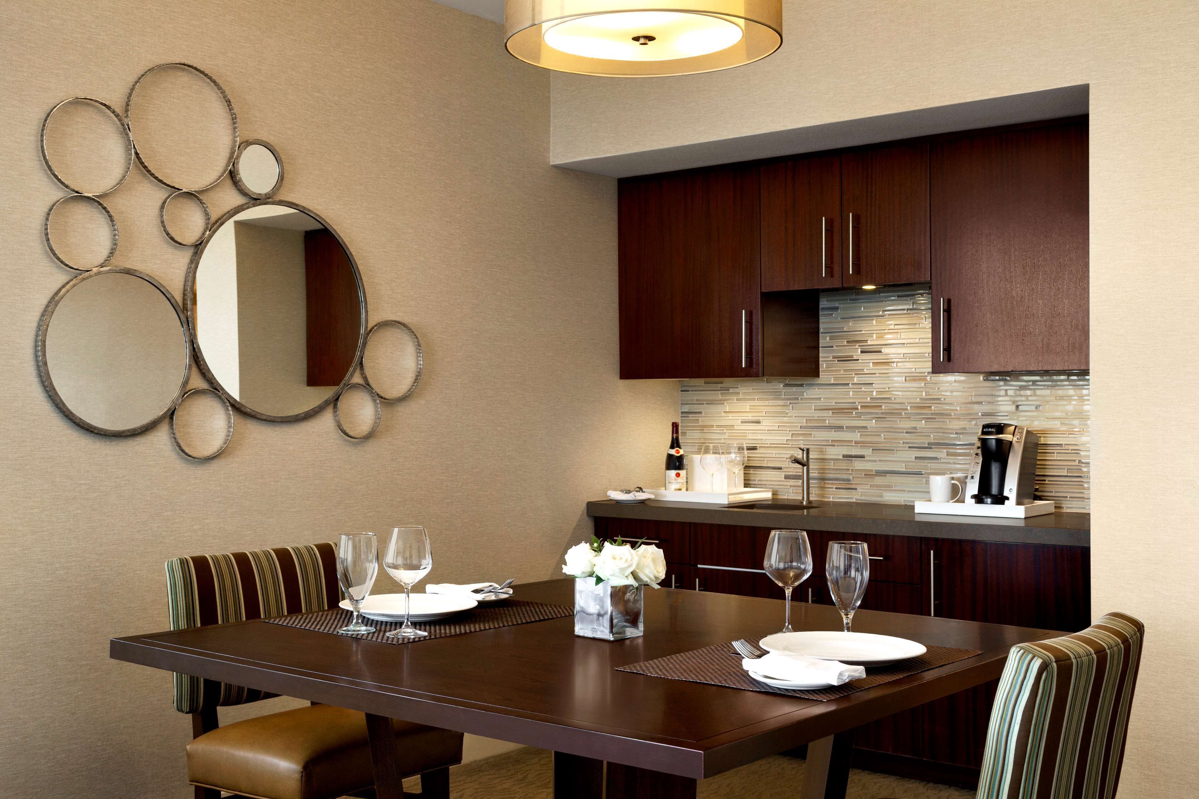 A dining area with a wooden table, chairs, and a decorative mirror.