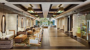 A spacious lobby with a long reception desk, comfortable seating areas, and a view of the outdoors. - Cape Rey Carlsbad Beach, a Hilton Resort & Spa (Carlsbad)