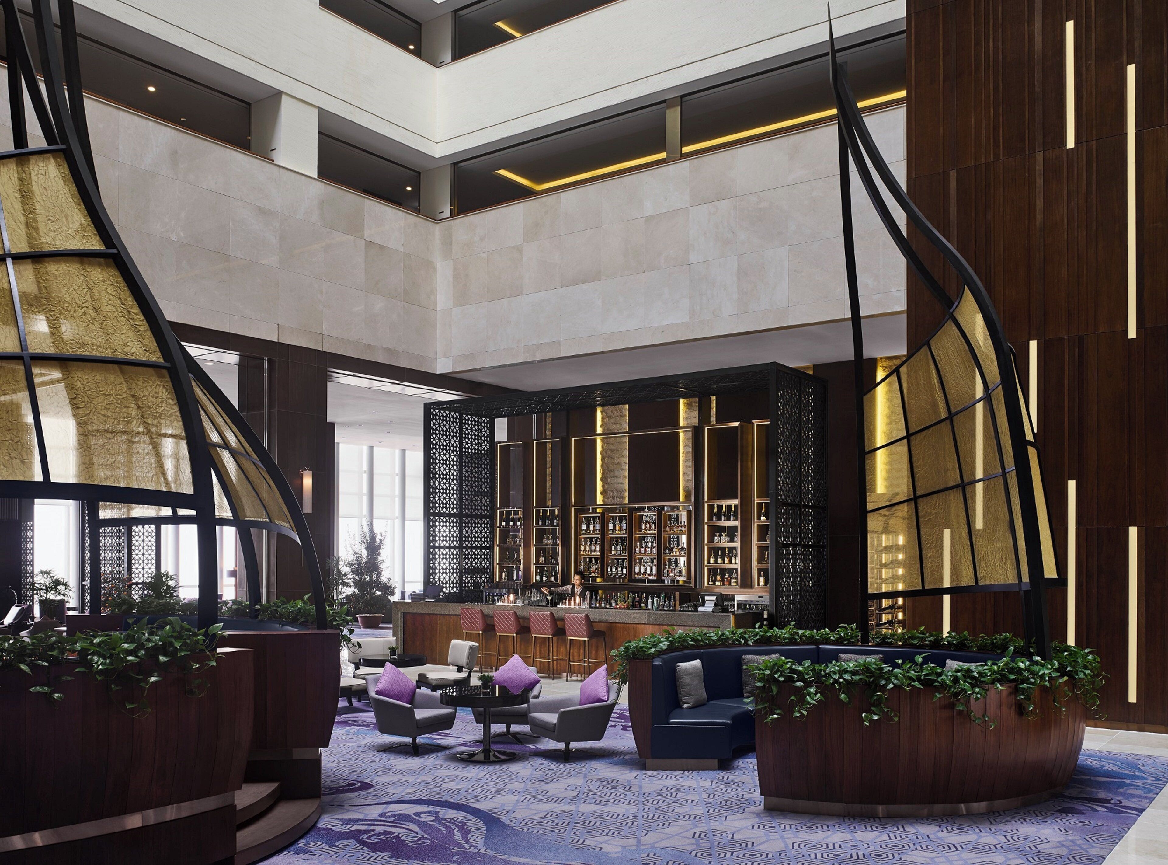 A spacious lobby with a bar area, seating arrangements, and a high ceiling with natural light.
