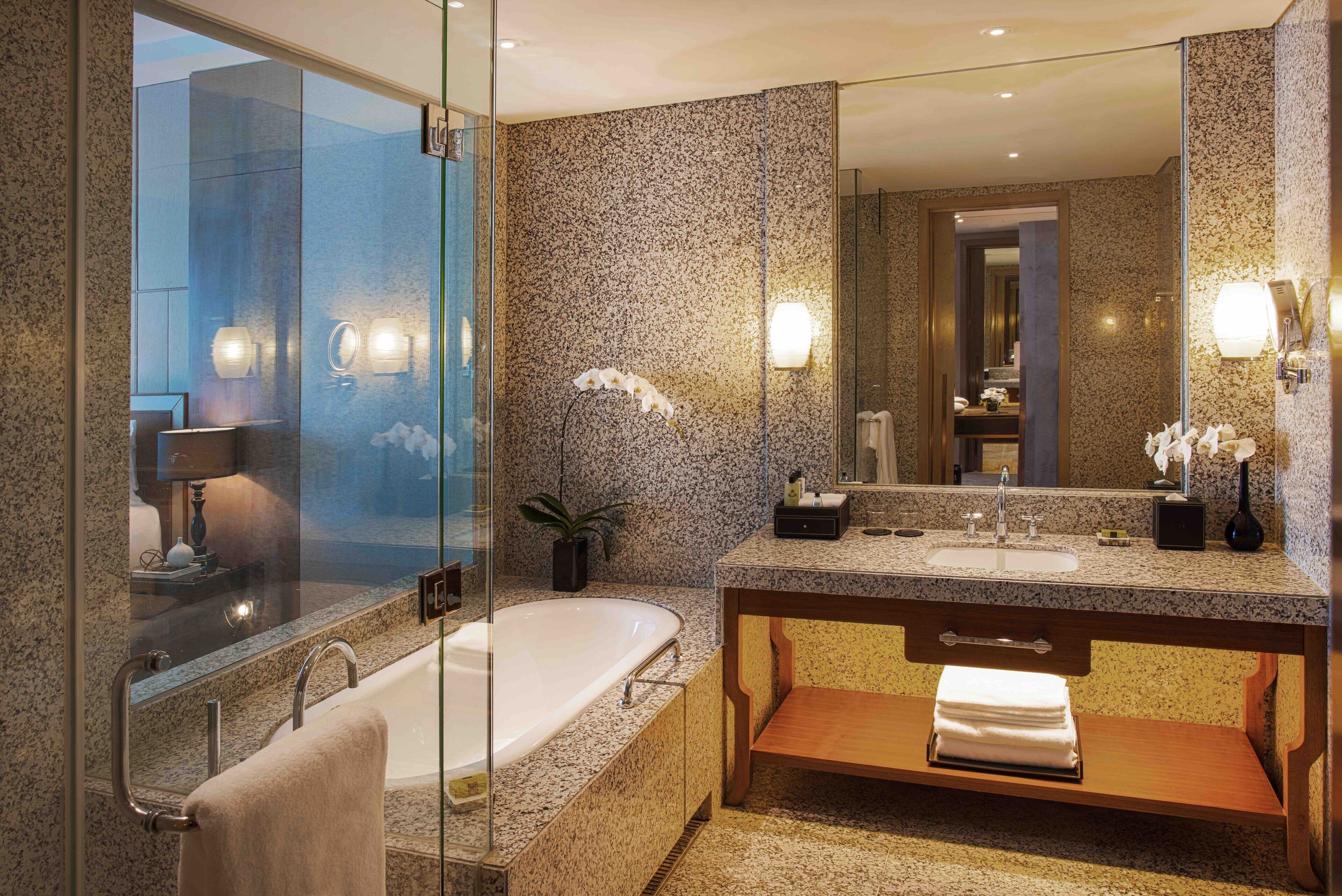A modern bathroom with a glass-enclosed shower, a freestanding bathtub, and a vanity with a large mirror.