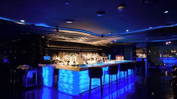 A bar area with a bar counter, stools, and a bartender.