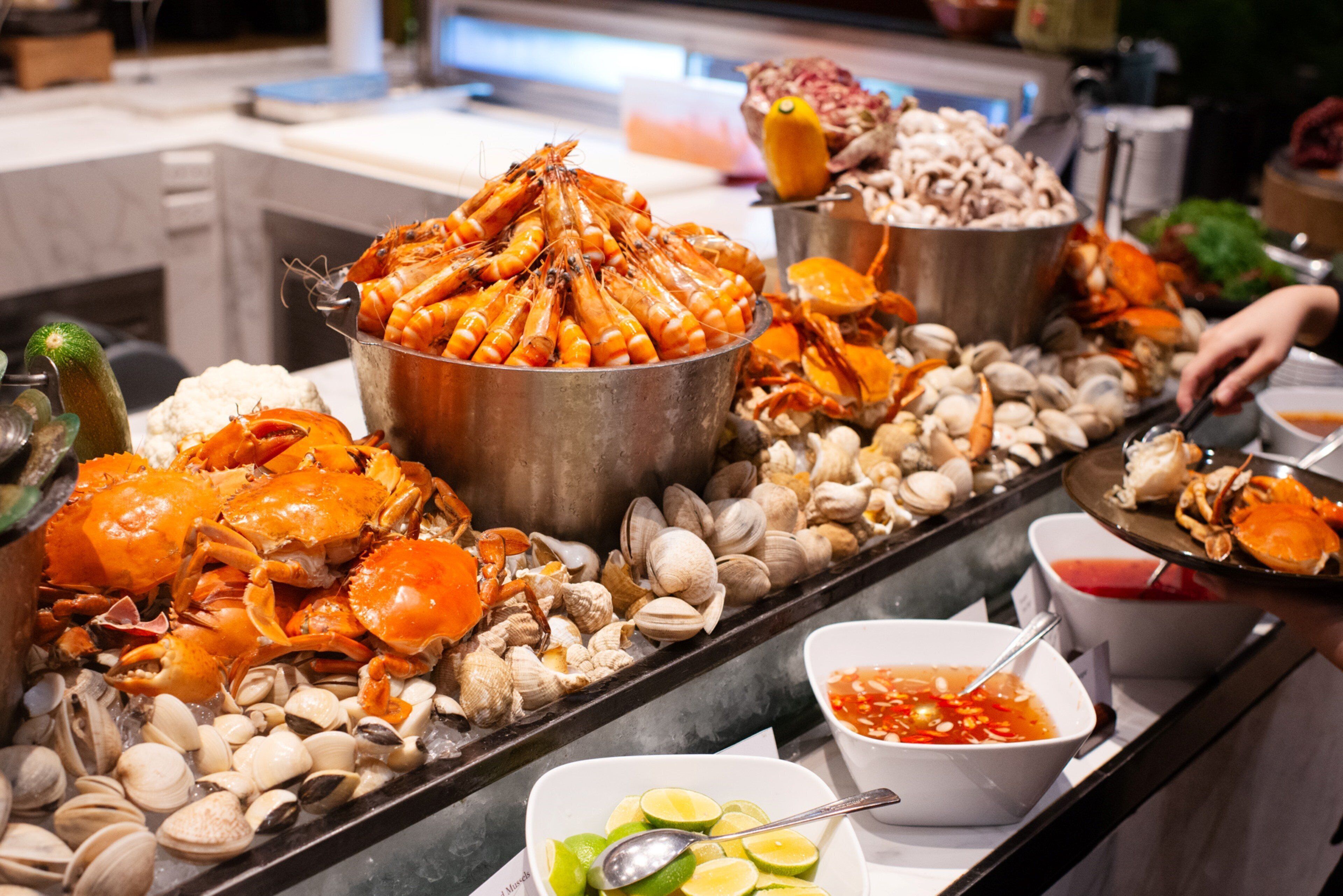 A buffet with seafood including crabs and clams, and a bowl of lime slices.