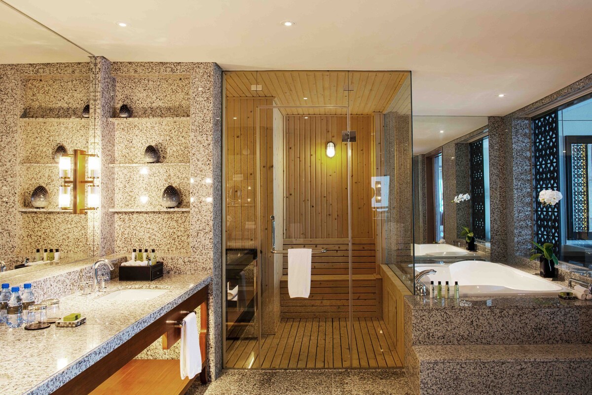 A modern bathroom with a granite countertop, wooden vanity, and a large mirror.