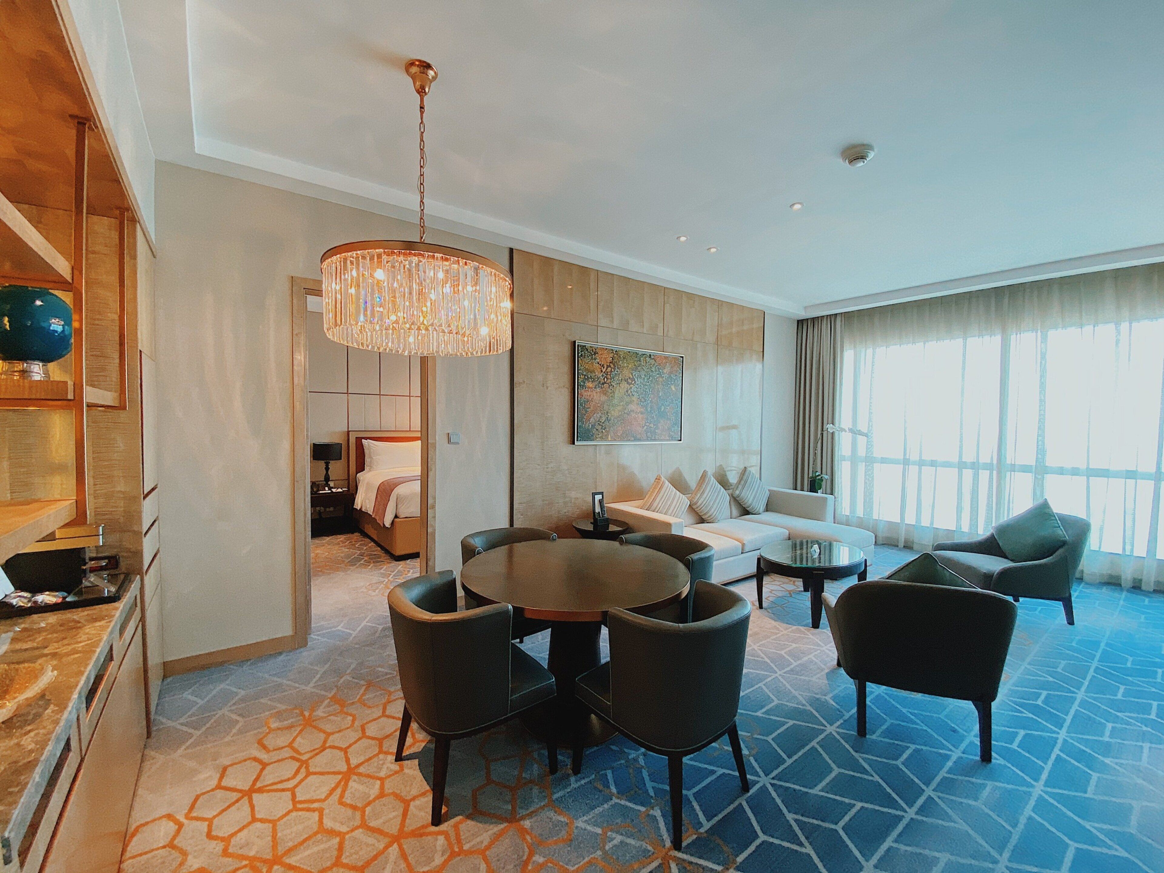 Une chambre d’hôtel comprenant un coin repas, un canapé, un lit et une grande fenêtre.