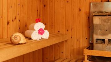 Un sauna de madera con bancos y una banca con toallas y flores.