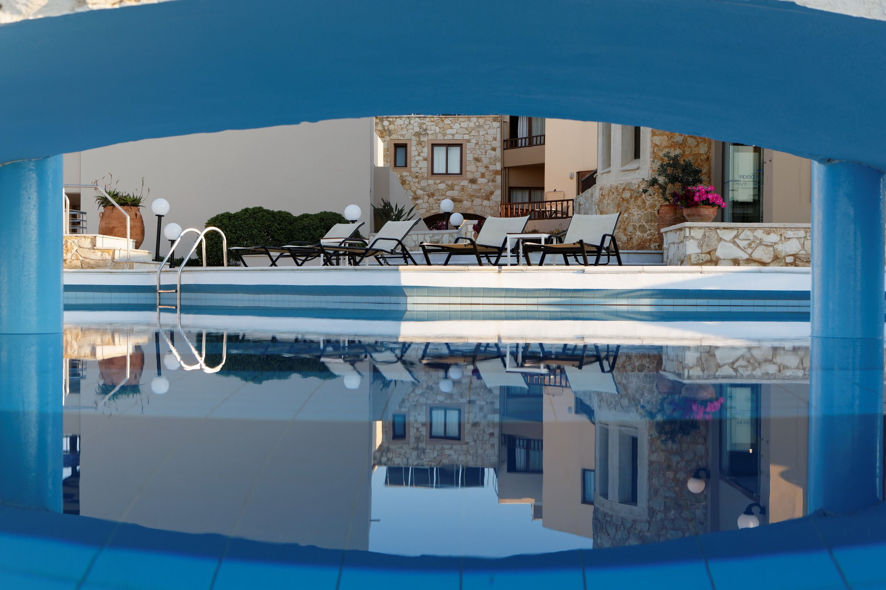 A pool area with lounge chairs and a stone building in the background.