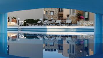 A pool area with lounge chairs and a stone building in the background.