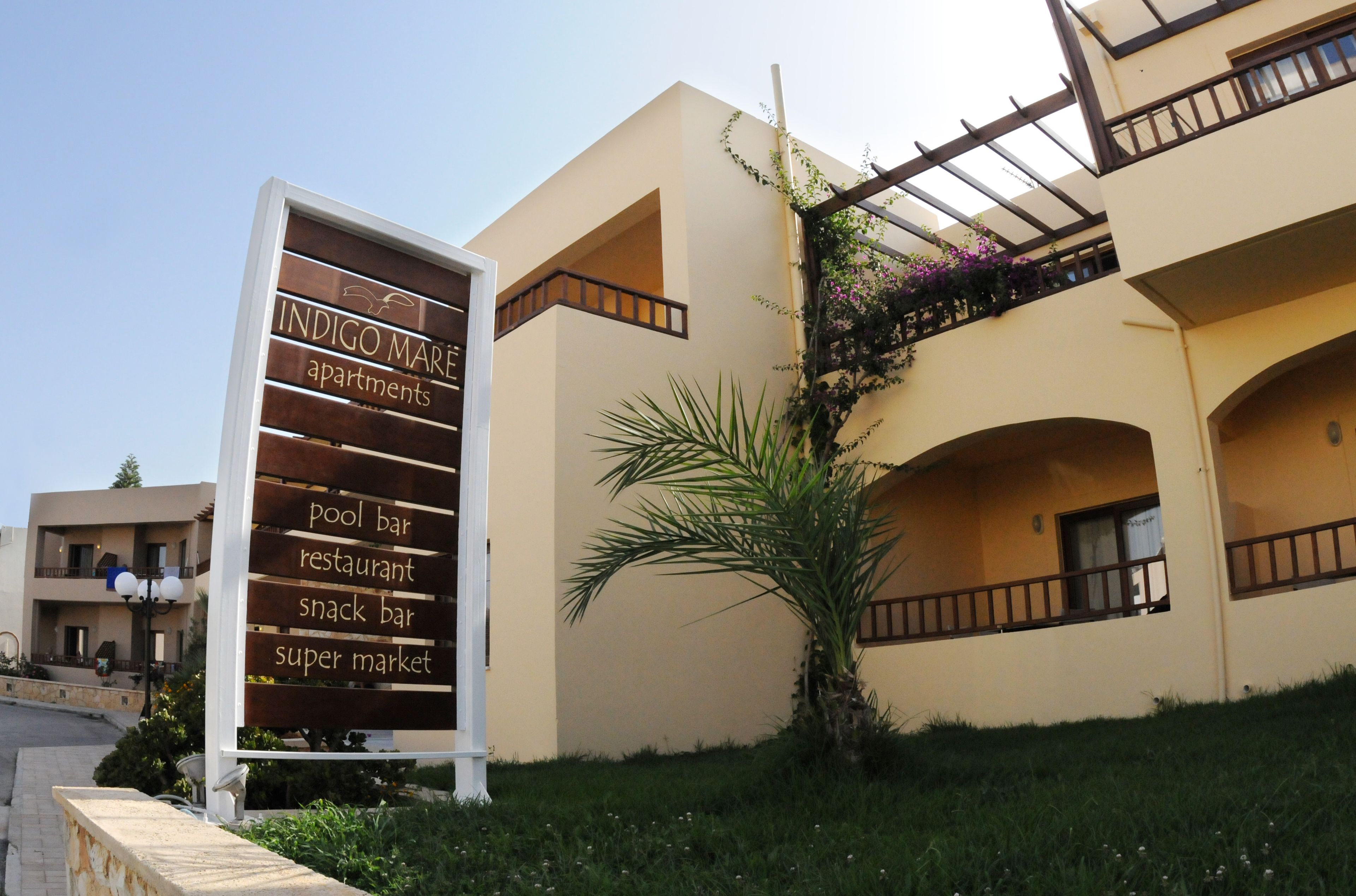 A signboard for Indigo Maré apartments listing amenities like a pool bar, restaurant, snack bar, and super market.