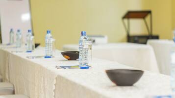 Una mesa de conferencias con botellas de agua, un bol y una pizarra de fondo.