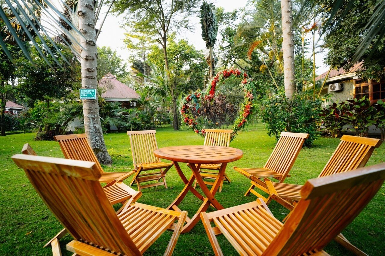 A garden area with a heart-shaped floral arrangement, wooden chairs, and a small table.