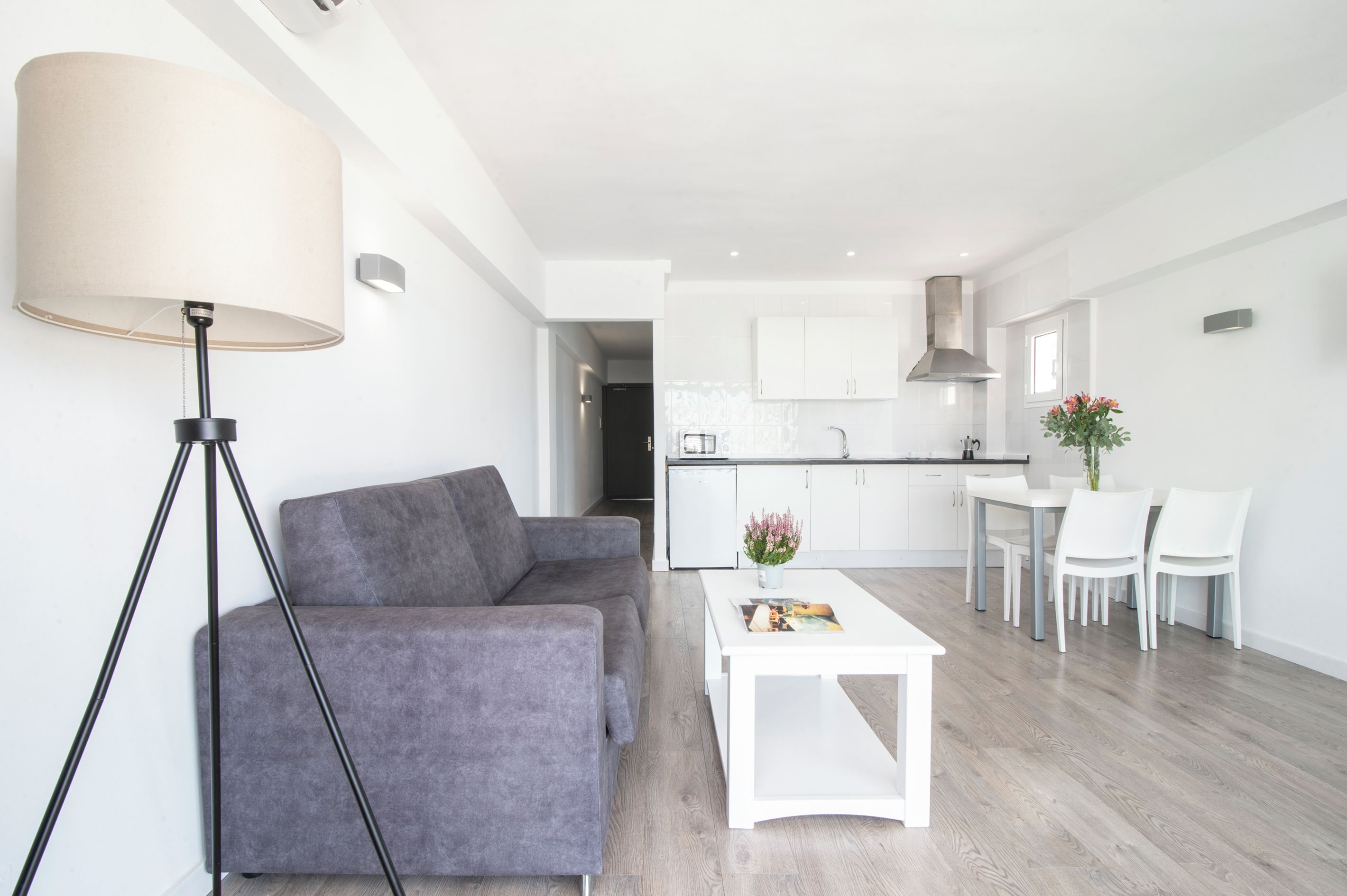 A modern living room with a grey sofa, a white coffee table, and a floor lamp.