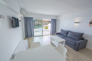 Un soggiorno moderno con un divano grigio, un tavolo bianco e un televisore a parete.