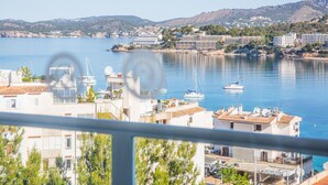 A coastal town with buildings near the water, a marina with boats, and hills in the background. - Pierre & Vacances Mallorca Portofino (Calvia)