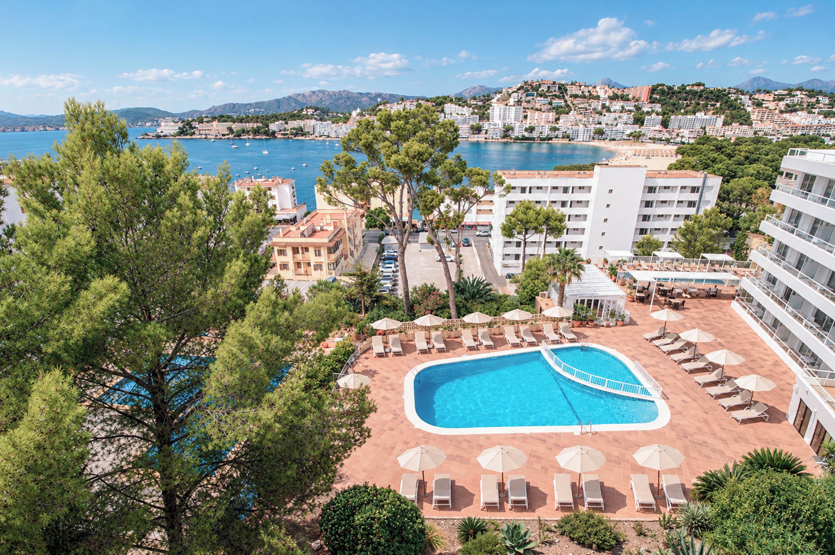 Un complejo turístico con piscina, sillones de descanso y vistas al mar y a las montañas.
