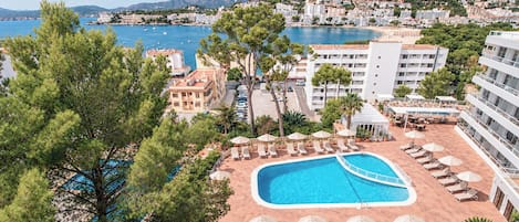 Et resort med swimmingpool, liggestole og udsigt over havet og bjergene.
