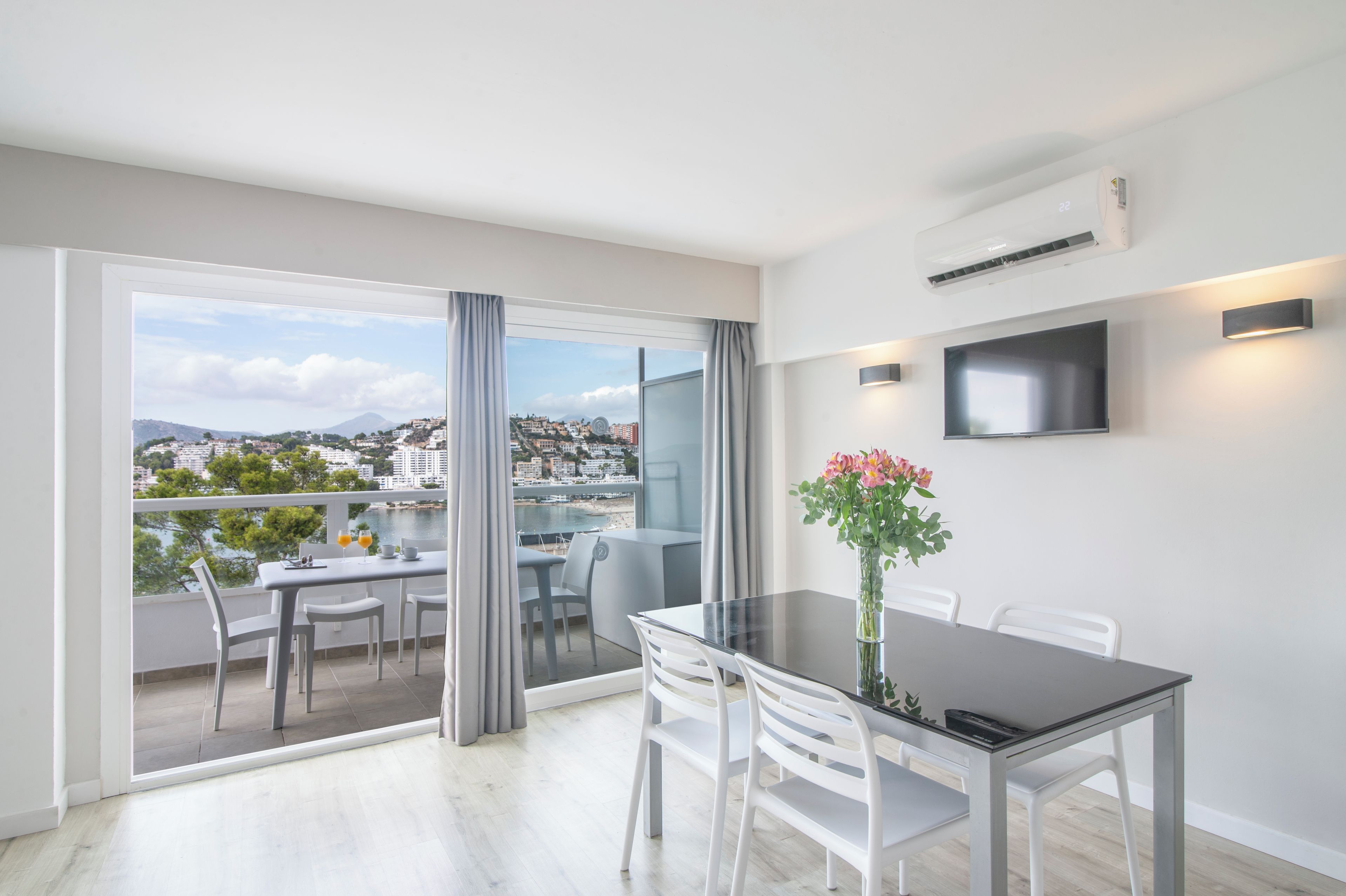 Un apartamento moderno con balcón, zona de comedor y televisor montado en la pared.