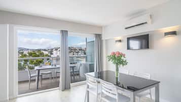 Un apartamento moderno con balcón, zona de comedor y televisor montado en la pared.