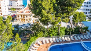 A resort with a swimming pool, lounge chairs, and a view of the sea and mountains. - Pierre & Vacances Mallorca Portofino (Calvia)