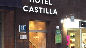 Exterior del Hotel Castilla, con entrada visible, un cartel que indica que es un hotel y banderas colgadas.