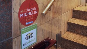 Una escalera de mármol con barandilla, un letrero circular rojo con el texto 'la guía MICHELIN 2013' y el logo de 'tripadvisor'.
