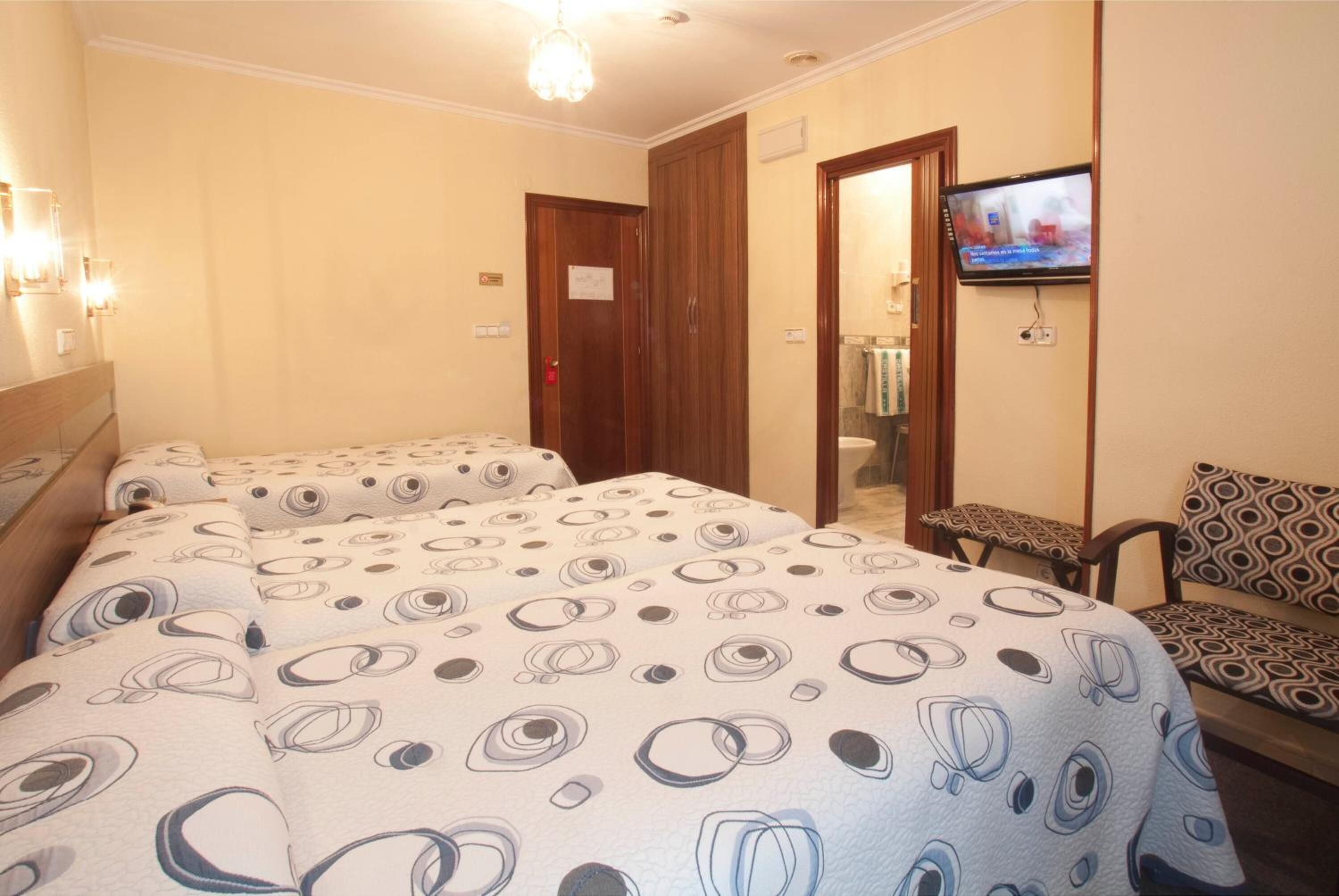 A hotel room with two beds, a television, a small table, and a chair.